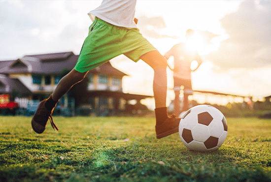 夕日の中でサッカーボールを蹴る少年